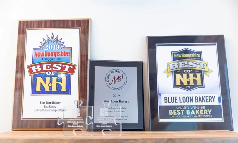 Award plaques on a shelf: New Hampshire Magazine Best of NH, Best Bakery 2019 and 2021, and a 2019 Center for the Arts sponsor plaque